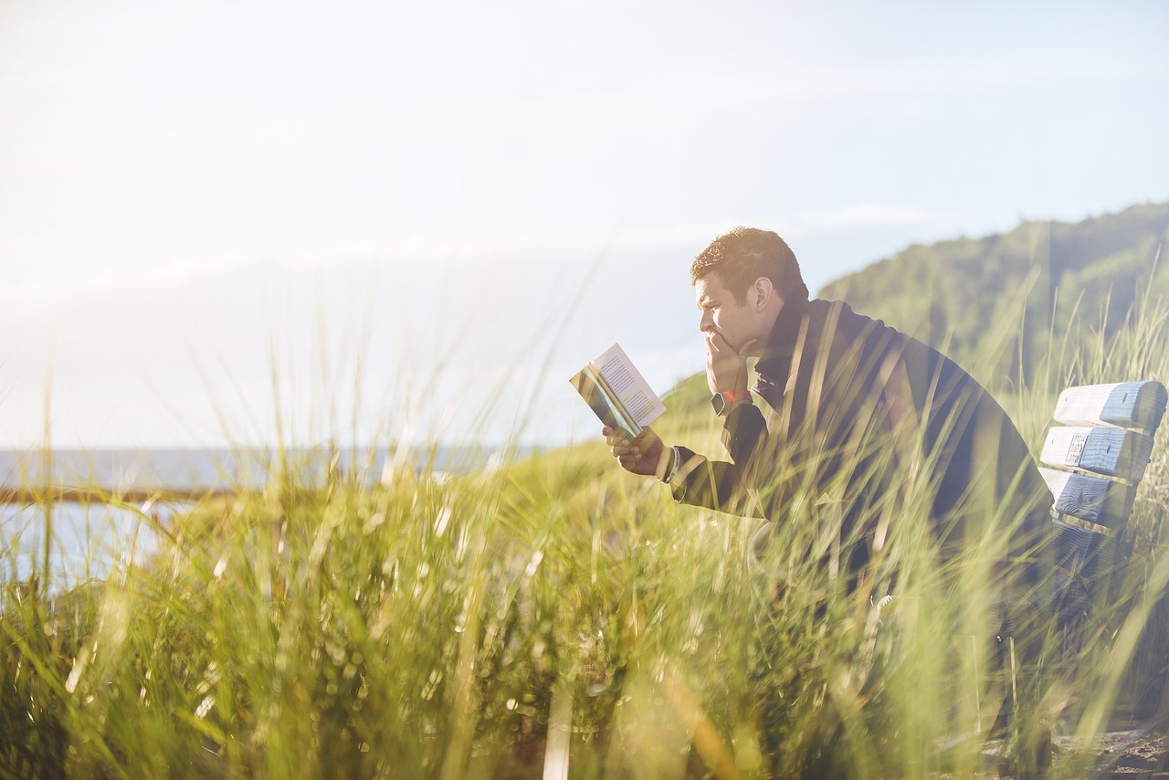 Man reading a book on a bench